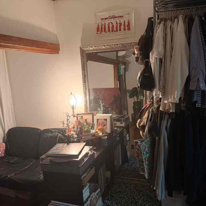 アイボリーの壁とブラックの家具が調和した1人暮らしの1Kの狭い部屋、大きな鏡とレコードプレーヤーがある雰囲気のある空間