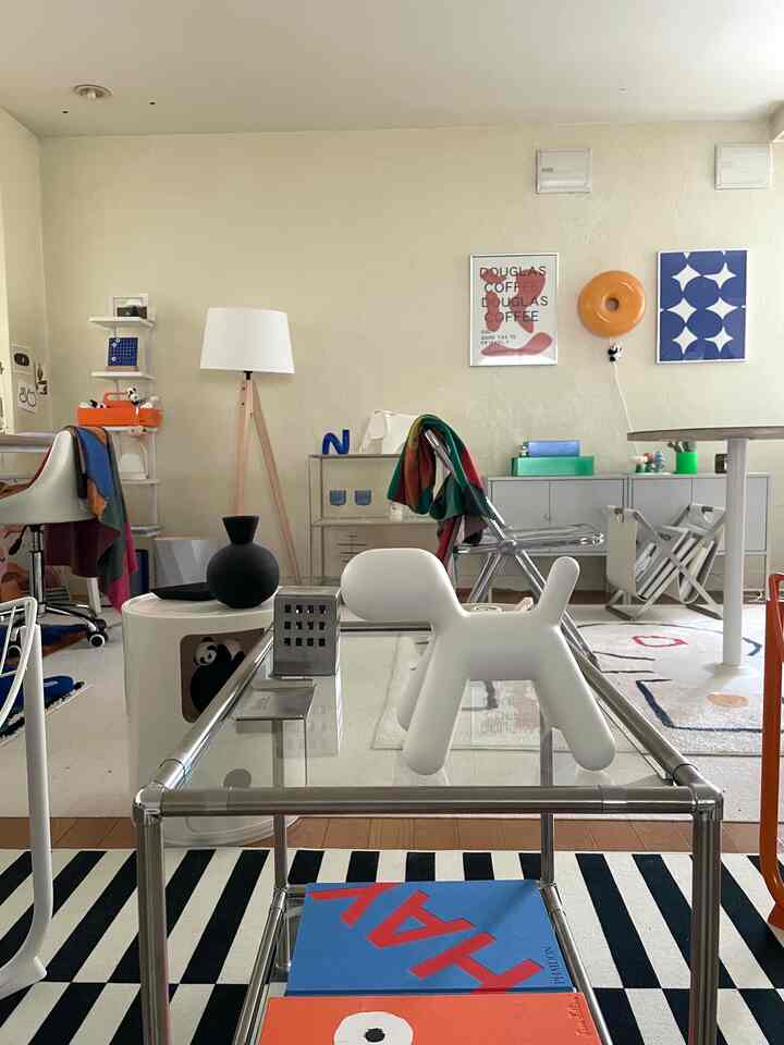 A white and gray toned living room featuring a dog-shaped sculpture, diverse furniture, and wall art in a mid-century modern style