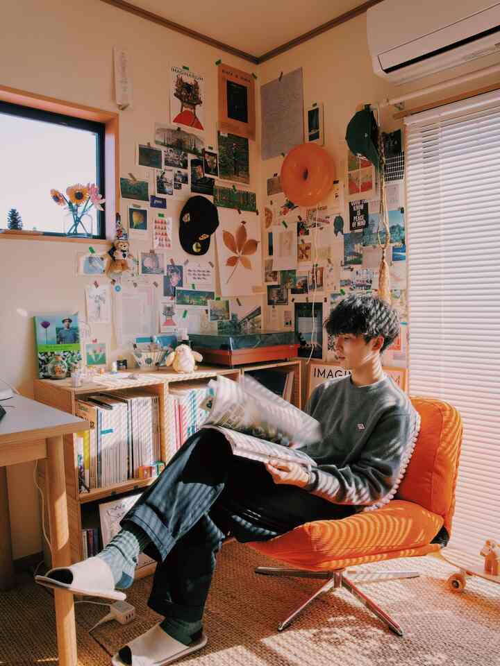 Cozy 6-tatami studio apartment with warm orange armchair, natural light, bookshelf, and relaxed single-person space