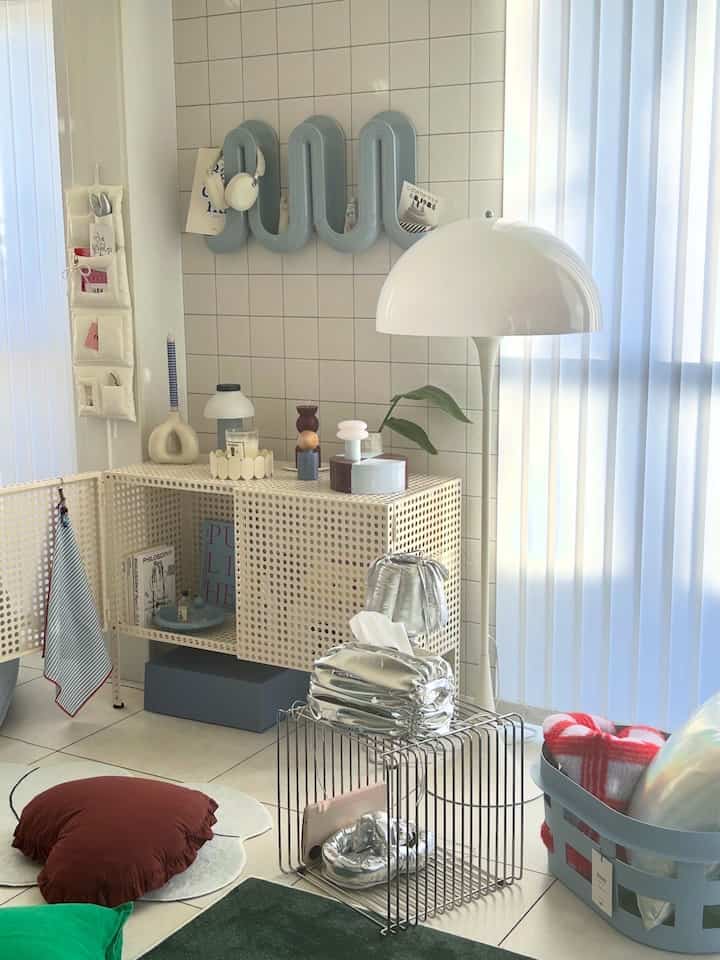 白とシルバーのトーンのリビングルーム、メタルシェルフとフロアランプが配置されたミニマルで明るい空間