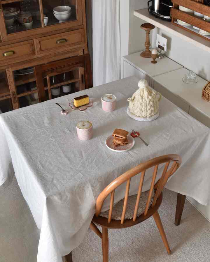 白いテーブルクロスとブラウンの木製家具が配置された北欧スタイルのダイニング、雰囲気のあるおうちカフェ空間