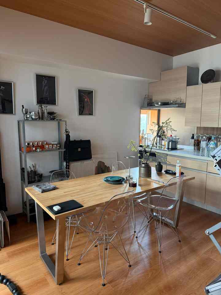 明るい木目調のナチュラルカラーが特徴の1LDKダイニングとキッチン空間、透明な椅子が配置された印象的なインテリア