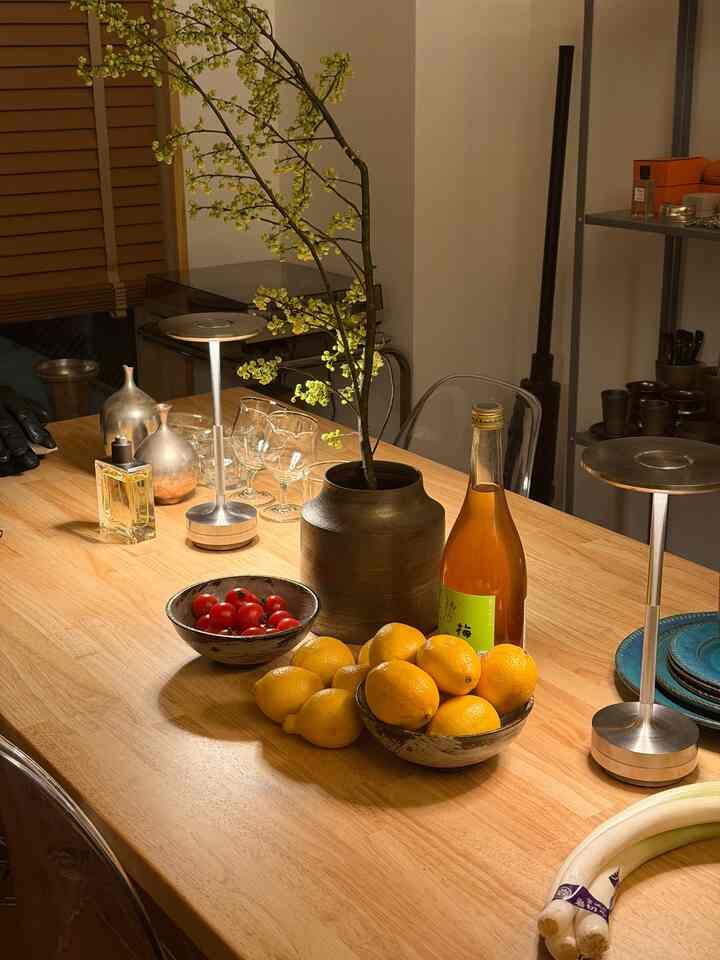 温かみのあるウッドトーンと黄色が特徴のダイニングスペース、花瓶や果物、ワイングラスが並ぶシンプルでモダンなインテリア