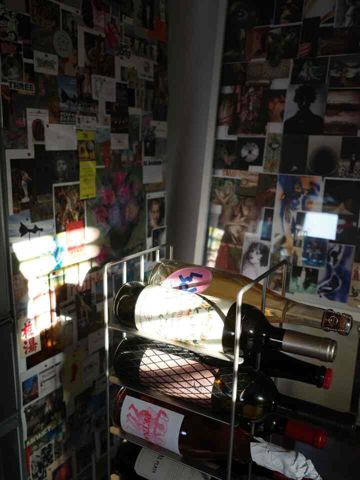 白を基調とした1LDKのスタジオ、ワインラックとポスターが飾られた壁が明るく居心地の良い空間を演出