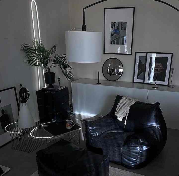 ブラックとホワイトのトーンによるミニマルなリビング、中央に大きなレザーのビーズクッションソファとフロアランプが配置された空間