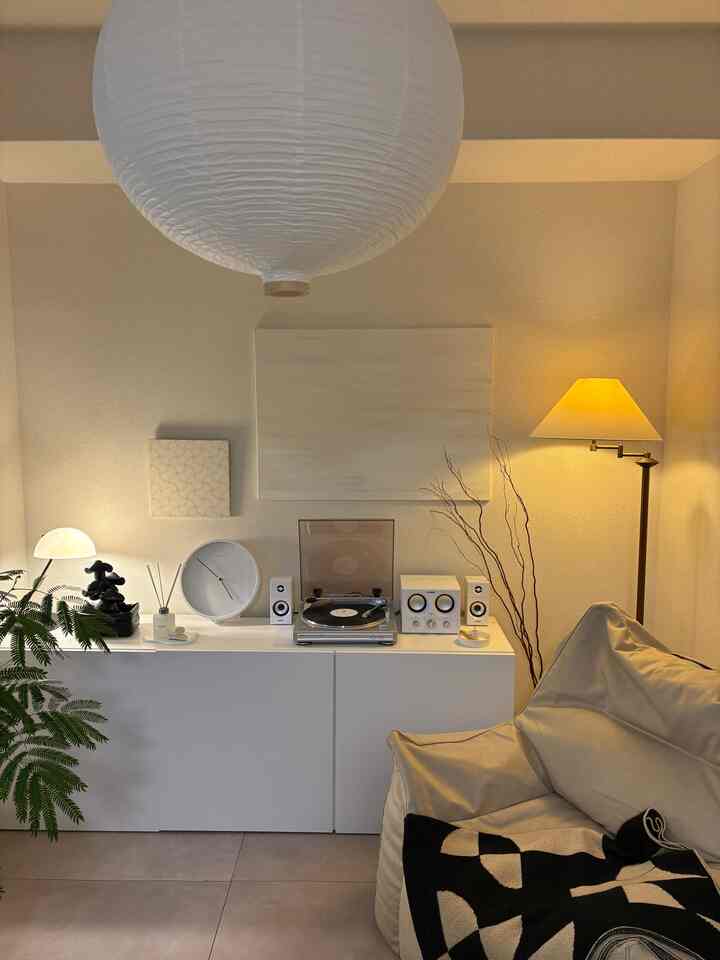 白とベージュの色調のリビング、BESTÅキャビネットとビーズクッション、暖かい間接照明が配置された雰囲気のあるインテリア