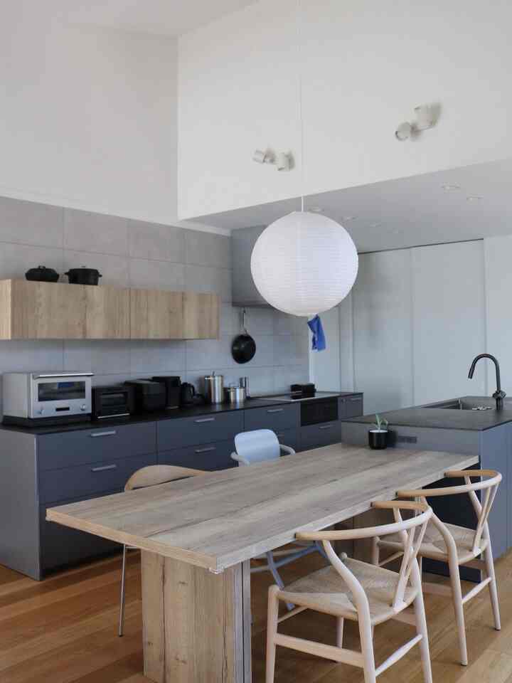 Bright white and wood tone compact kitchen dining room featuring a natural modern dining table and chairs
