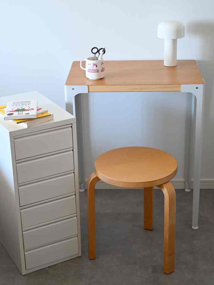 白い壁と木目のデスク、スツールが配置されたシンプルなホームオフィスのインテリア