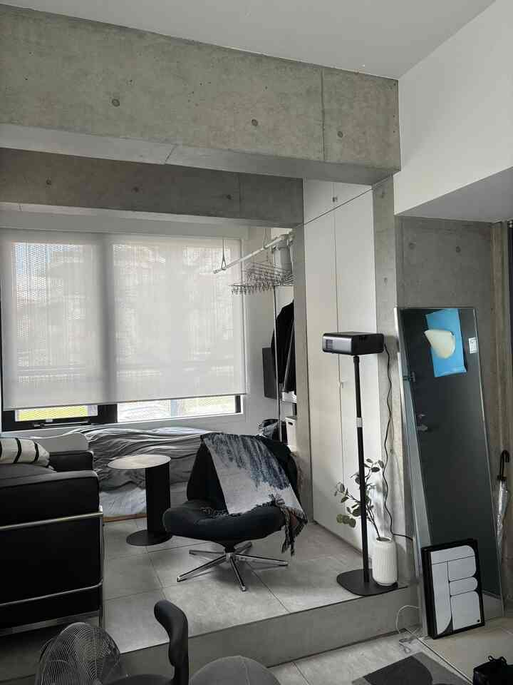 Monotone studio apartment living room featuring black armchair and side table, minimalistic and calm atmosphere overall