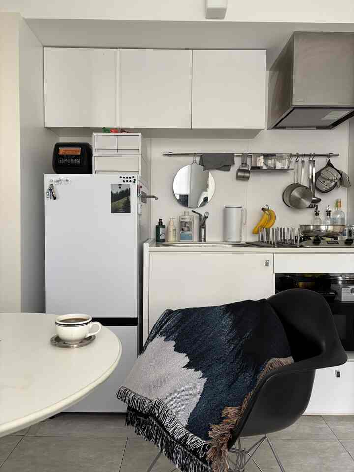 白と黒のモダンなキッチン空間、白い冷蔵庫とシンク、黒い椅子が配置されたすっきりとした印象のインテリア