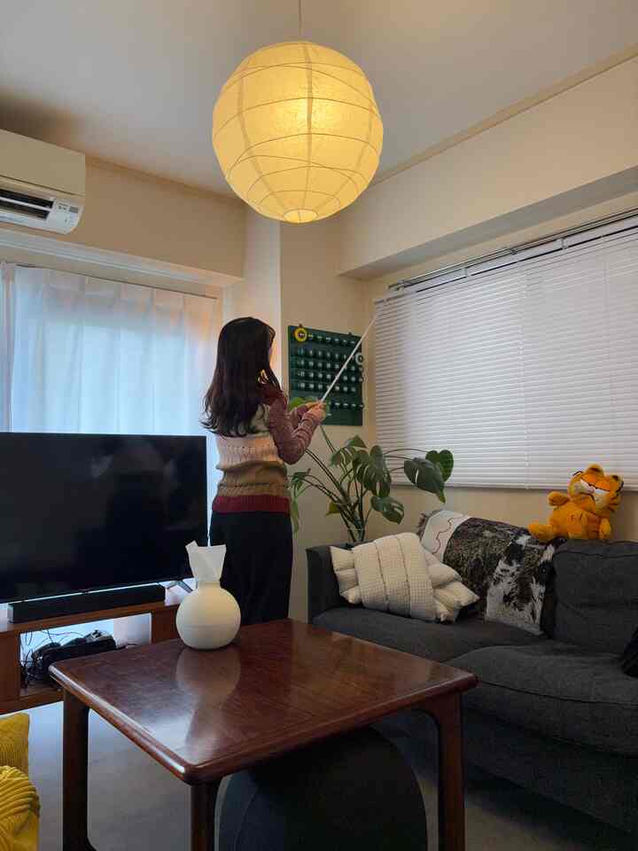 白を基調としたリビング、子供とグレーのソファと木製テーブルが配置され、カーテンとブラインドが調和した雰囲気のある空間