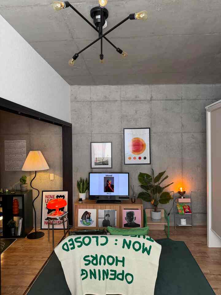 ナチュラルな木目調とコンクリート壁が調和したリビング、テレビ台とフロアランプが配置された雰囲気のあるインテリア