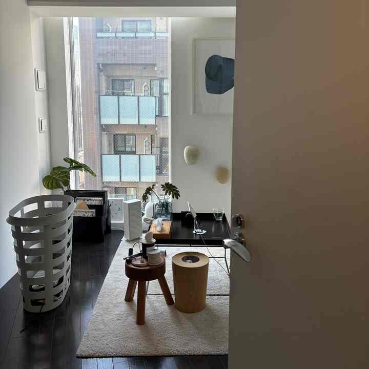 白い壁とナチュラルウッドのスツール、黒いコーヒーテーブルが配置された印象的なナチュラルモダンの玄関スペース