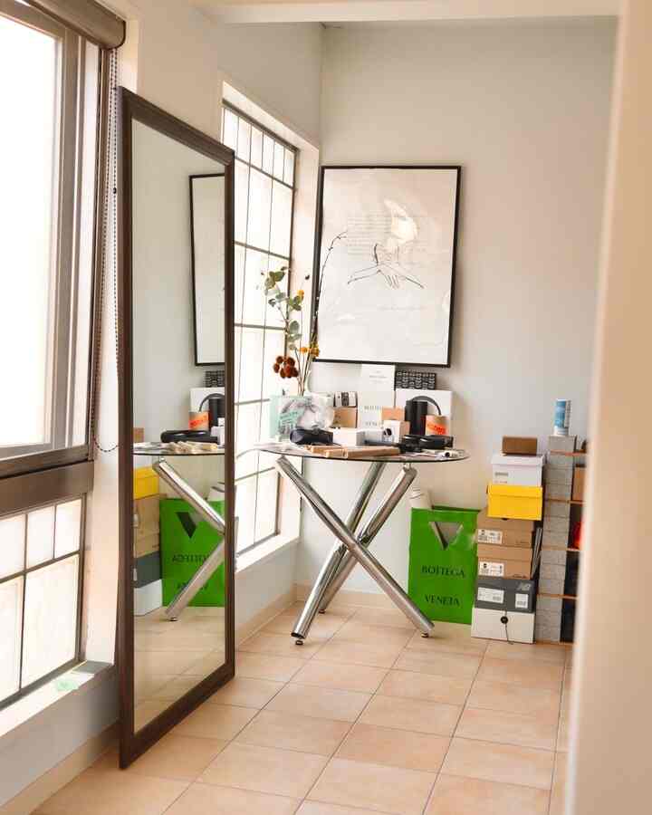 白い壁とベージュの床の狭い部屋、窓際に大型の全身鏡とカフェ風のテーブルが置かれた清潔感あるホームカフェ空間