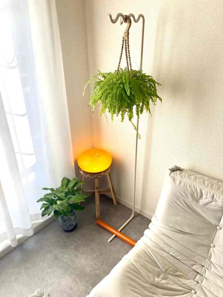 白と木目調の調和が取れた一人暮らしのリビングコーナー、観葉植物と黄色いランプが温かみのある雰囲気を演出