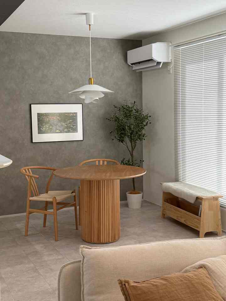 ナチュラルな木目とホワイトカラーが調和したモダンなジャパンディスタイルのダイニング、丸い木製テーブルと椅子、大きな観葉植物が配置された印象的な空間