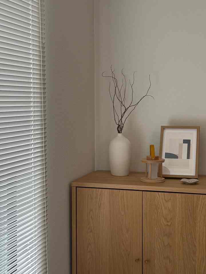 Natural color and wood tone living room corner featuring simple decor with minimal picture frame and vase