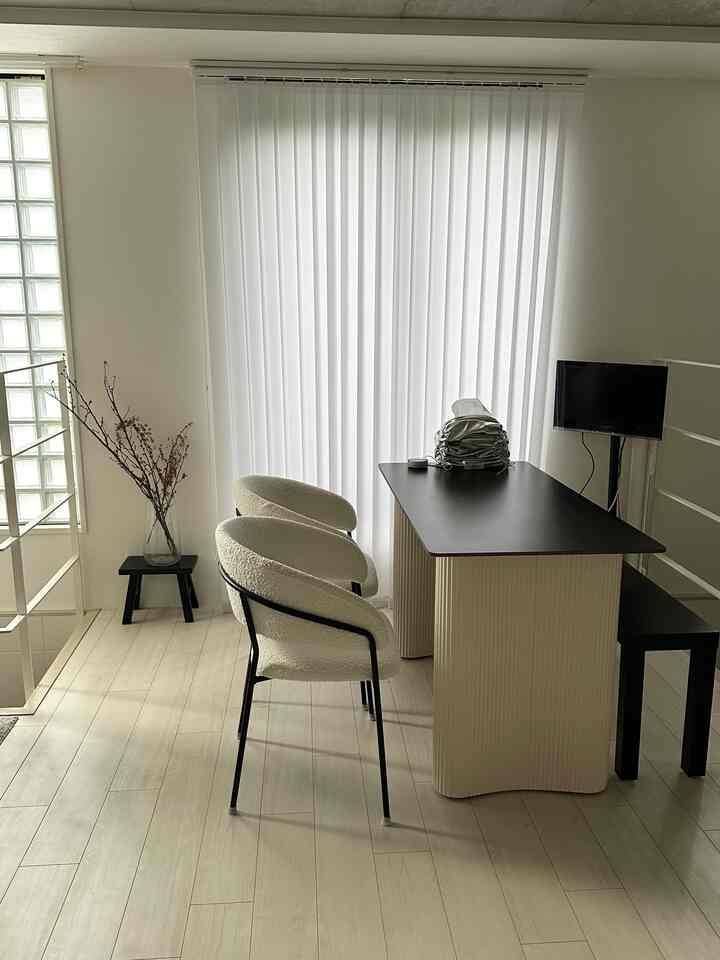 白と黒の色調の1LDKリビング、ダイニングテーブルとスツールが配置されたモダンで清潔感のある空間