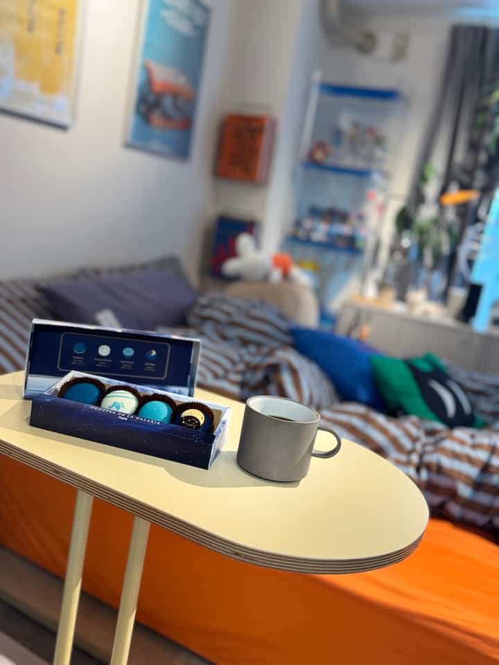 A studio apartment featuring a pale yellow side table and orange sofa bed, creating a cozy and comfortable atmosphere