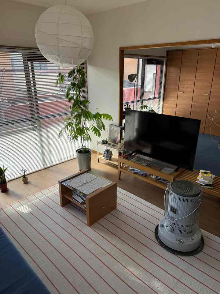 木目調のナチュラルなリビング、窓にブラインド、青いソファと木製のコーヒーテーブルが配置された落ち着いた空間