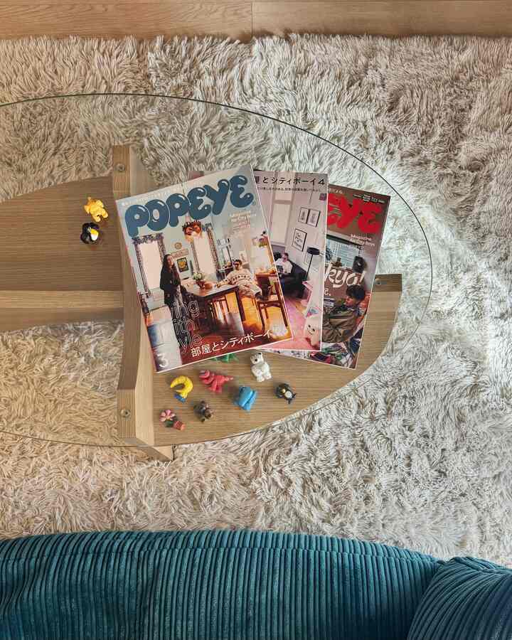 白いシャギーラグと木目調のコーヒーテーブル、ブルーソファが配置された落ち着いた二人暮らしのリビング