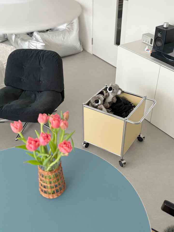 A natural-toned living room featuring a bright beige storage box and a black armchair