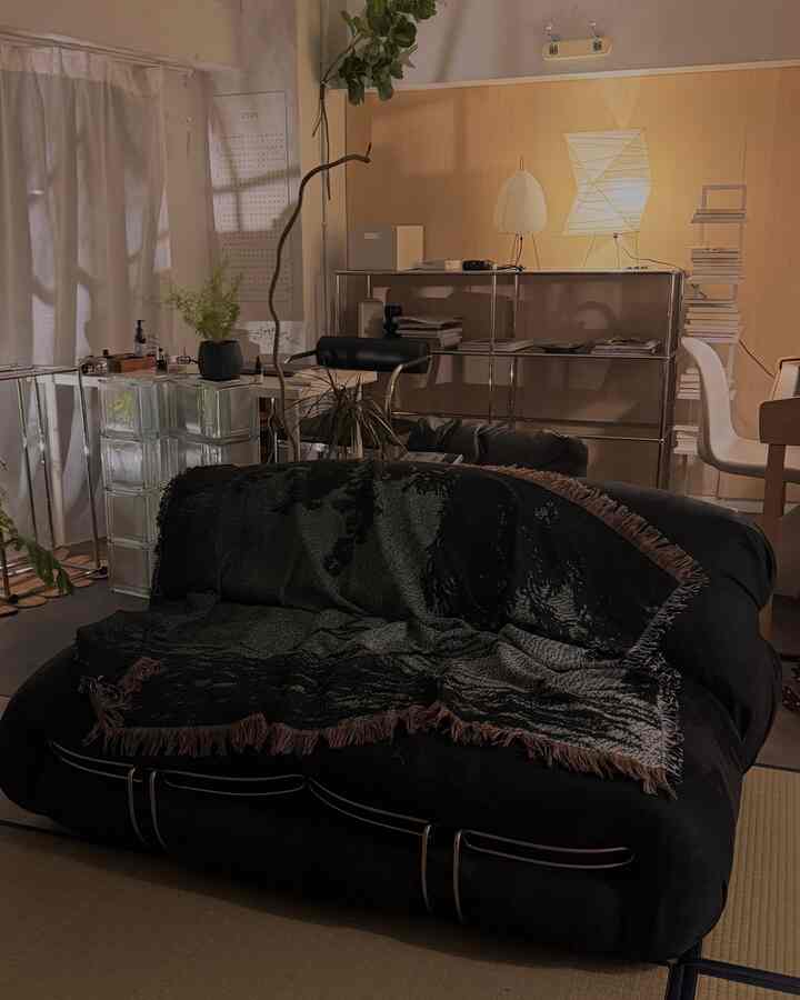 Natural toned living room with tatami floor, featuring a black sofa and floor lamps creating a warm atmosphere
