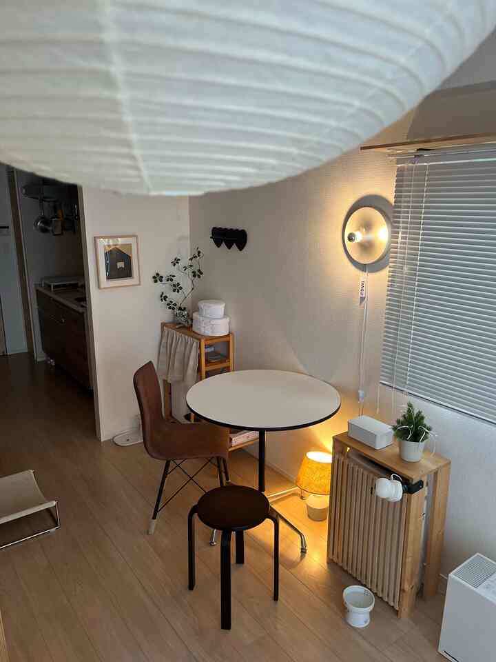 ブラウンの木目調と白を基調とした1LDKのダイニング、スツールとダイニングチェアが配置された落ち着きのある空間