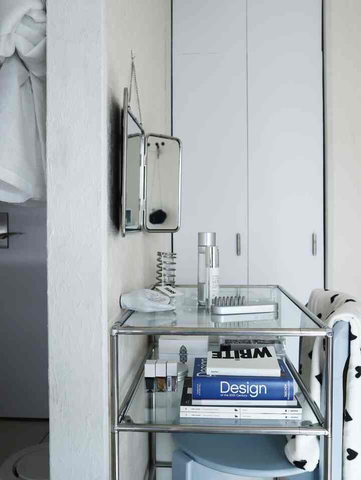 白とステンレス調の化粧台空間、ミニマルな鏡と整理された化粧品が配置されたすっきりしたインテリア