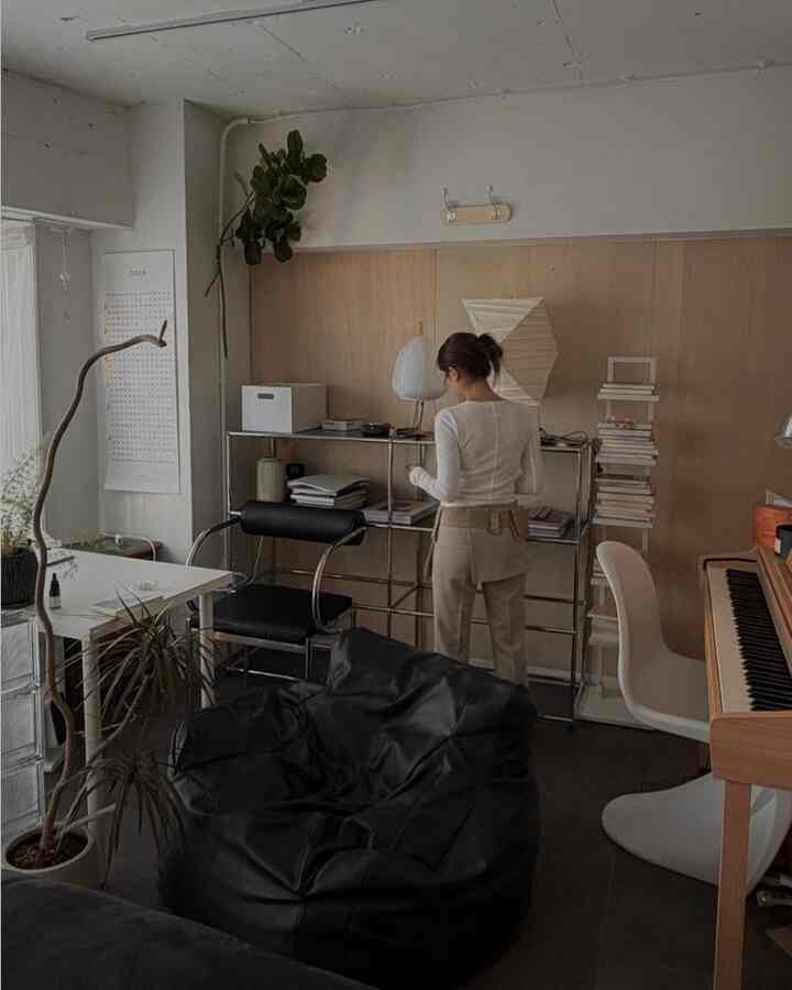 ブラックとホワイトのトーンが調和するホームオフィス兼趣味の空間、ビーンバッグとデスク、ピアノが配置された落ち着いた雰囲気の部屋