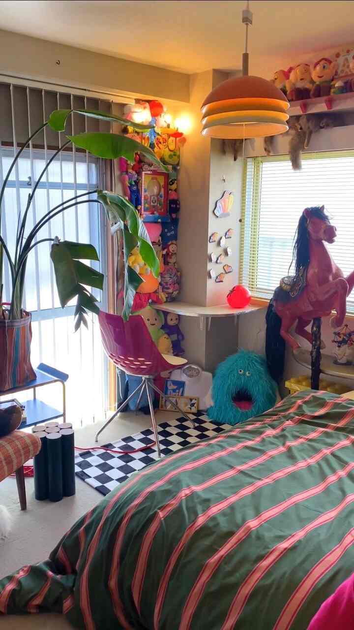 赤と緑を基調とした寝室、観葉植物とレトロなおもちゃが配置された雰囲気のあるインテリア