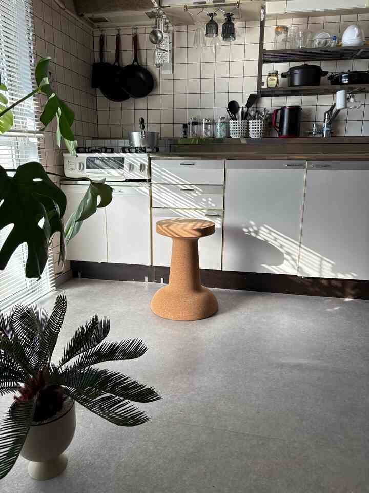 白いタイルとコルクスツールが配置された明るいキッチン、自然光が差し込む雰囲気のあるインテリア