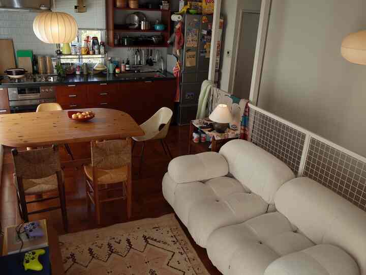 ホワイトとブラウンの色調のリビングとキッチンの空間、ウッドのダイニングテーブルとソファが配置された雰囲気のあるミッドセンチュリーモダンのインテリア