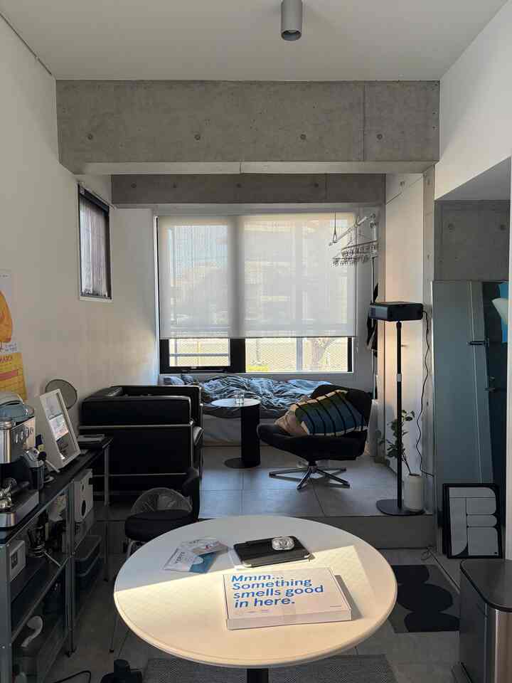 Modern and minimal studio apartment with white and black tones, featuring sofa, armchair, and coffee table