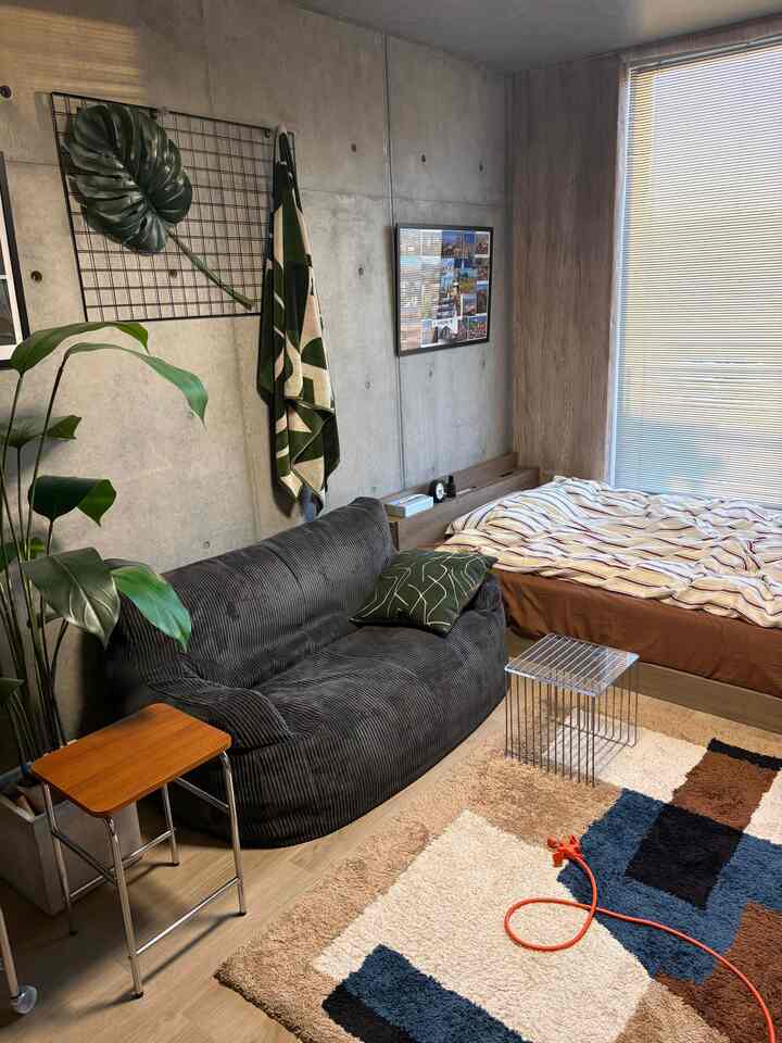 Beige and brown toned modern 7.5-tatami single household bedroom featuring black bean bag sofa and side tables in relaxed interior
