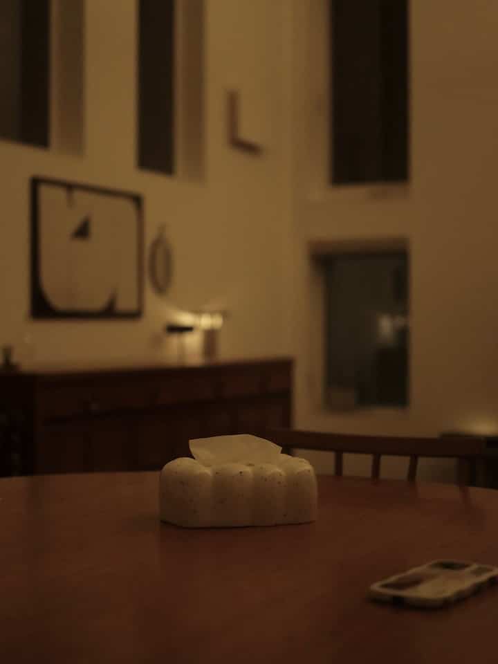 暖かみのあるブラウン調のダイニングルーム、中央に白いティッシュケースが置かれた木製テーブルが配置されたシンプルでナチュラルな空間