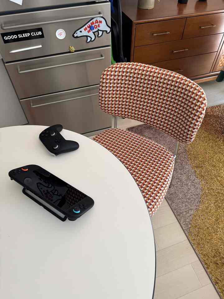 A compact space with a white round table and patterned stool, featuring a game console and controller creating a game room vibe