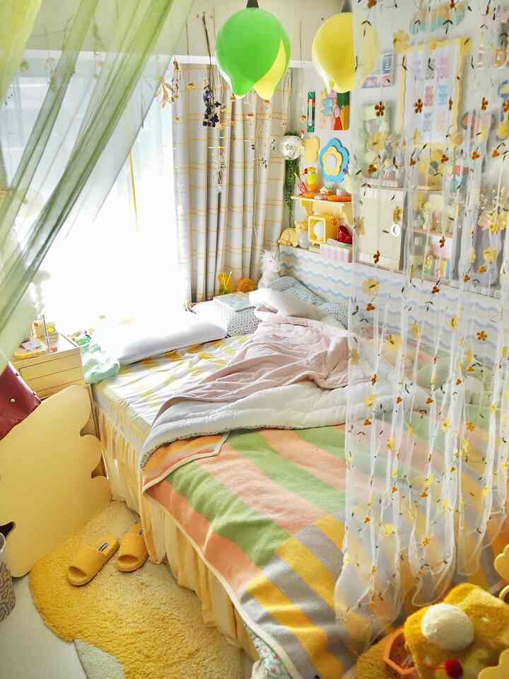 明るい黄色とパステル調が調和した可愛らしい寝室、多彩な寝具と風船型照明が配置された雰囲気のあるインテリア