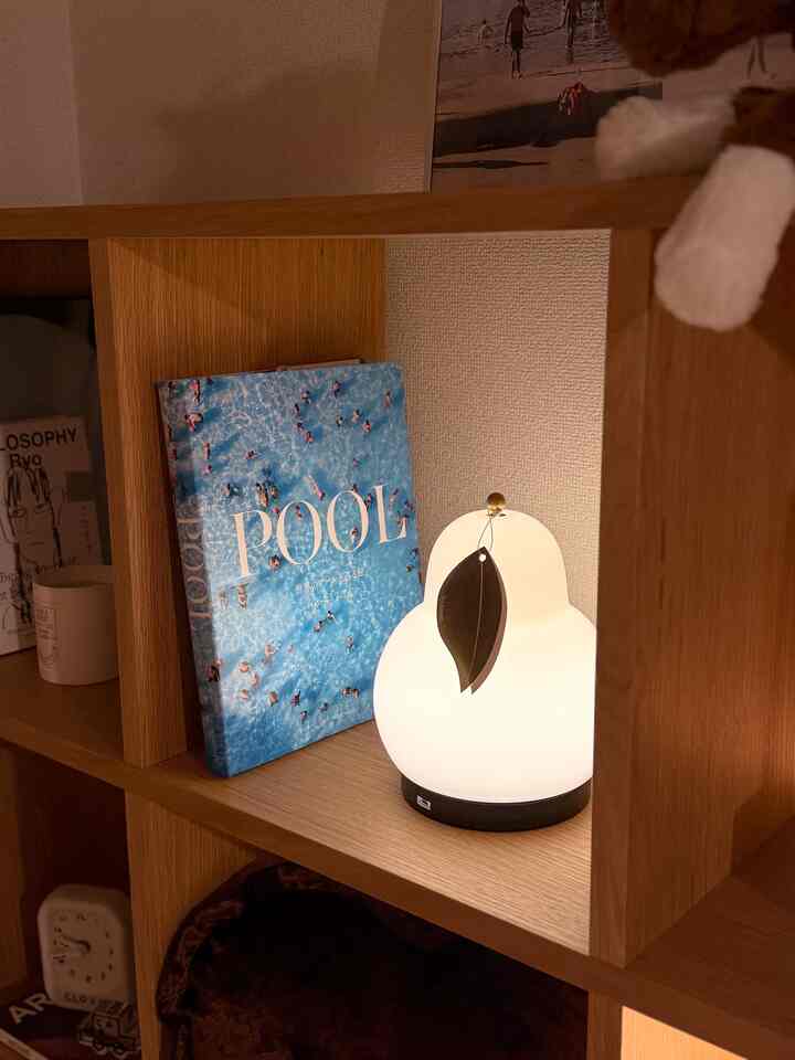 Warm wood tone bookshelf featuring a white table lamp in a cozy Korean interior space