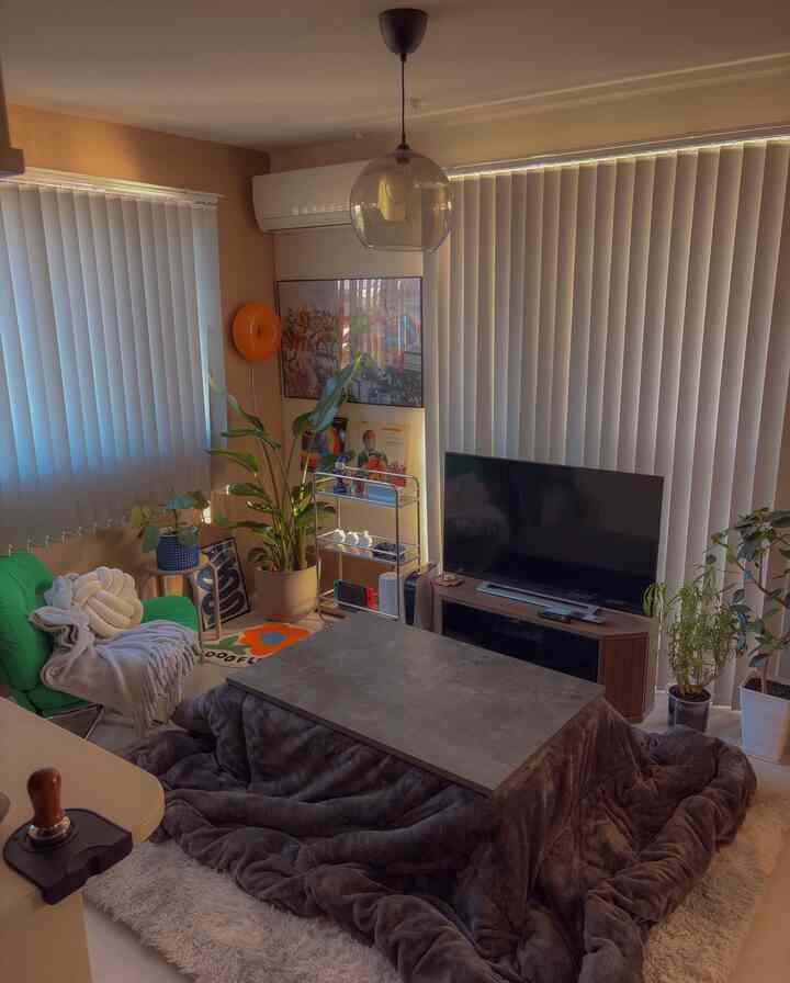 ブラウンとグリーンの色調のリビング、こたつテーブルとアームチェア、テレビ台が配置された雰囲気のある空間