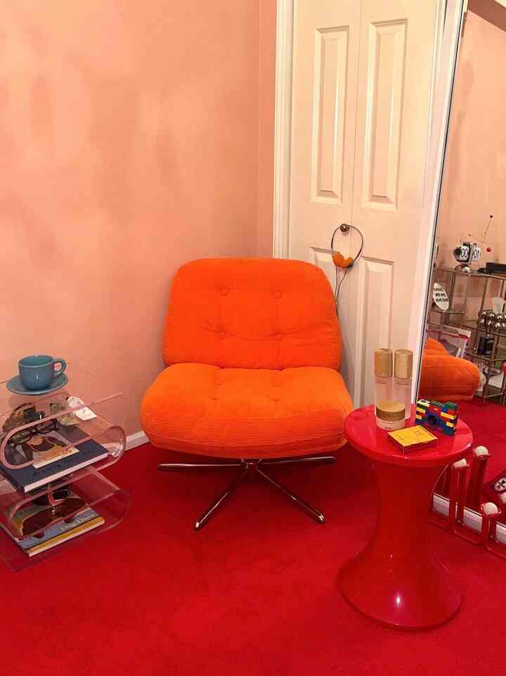 オレンジのアームチェアと赤いラグが印象的な小さな部屋の角の空間