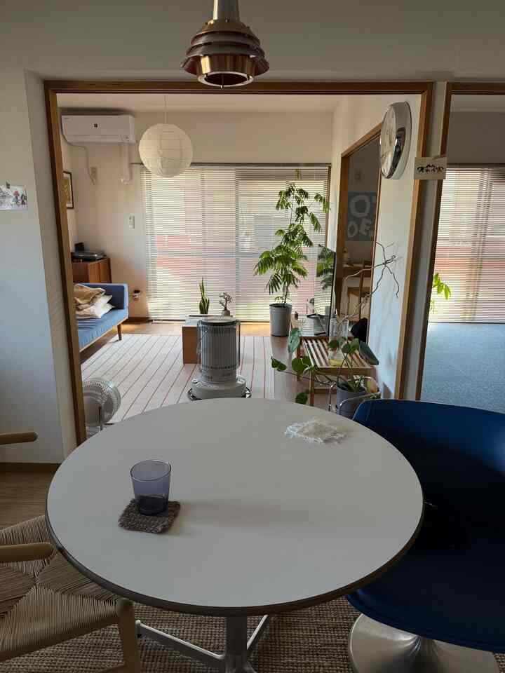 White and natural tone living and dining room featuring plants, sofa, and round dining table with a cozy atmosphere