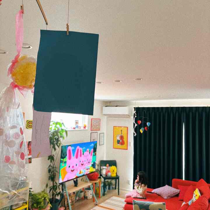 ブラックのカーテンと赤いソファが配置されたコンパクトなリビング、子供のいる家族の空間