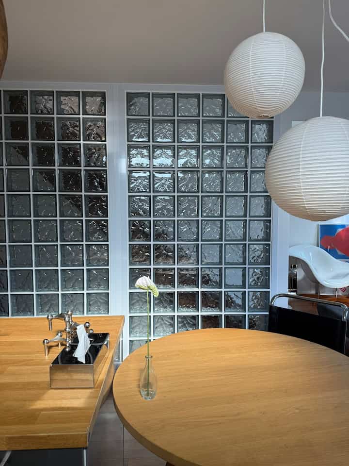 Clean dining room dominated by white and wood tones, featuring a round dining table and two paper pendant lights