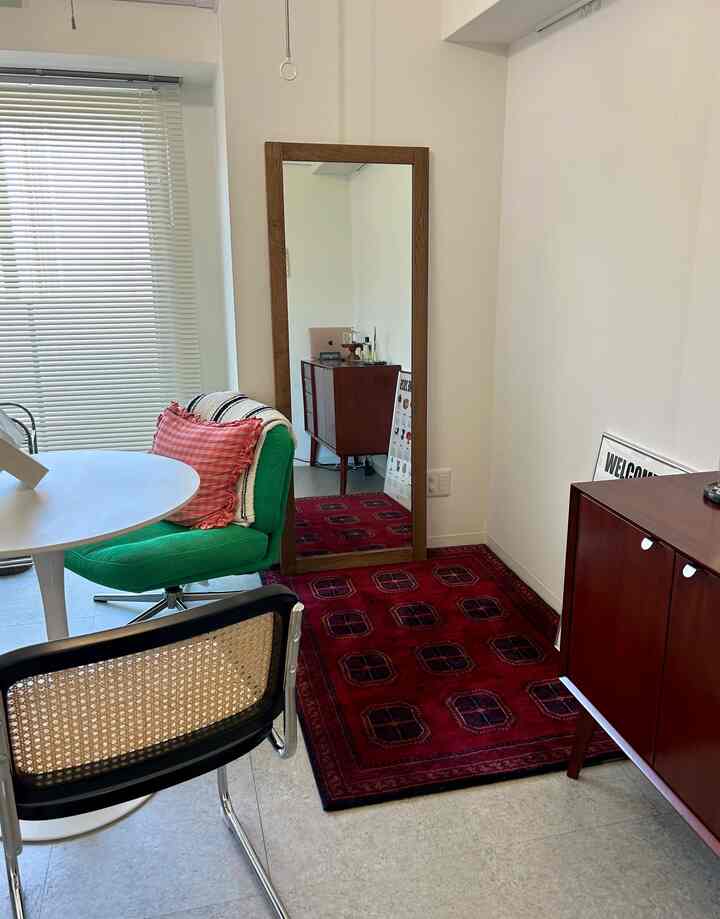 赤いカーペットと緑のアームチェアが配置された、ミッドセンチュリーモダンの1K一人暮らしの空間