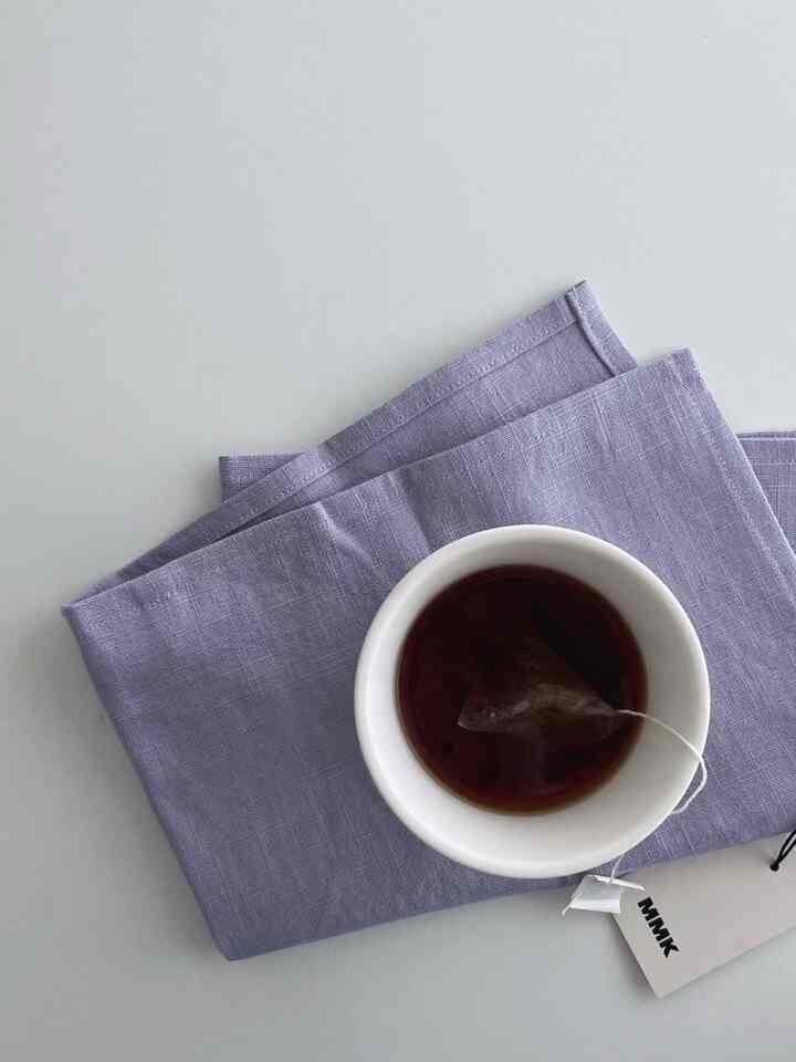 ラベンダー色のリネンキッチンタオルと紅茶のカップが置かれたシンプルでナチュラルなキッチンのインテリア