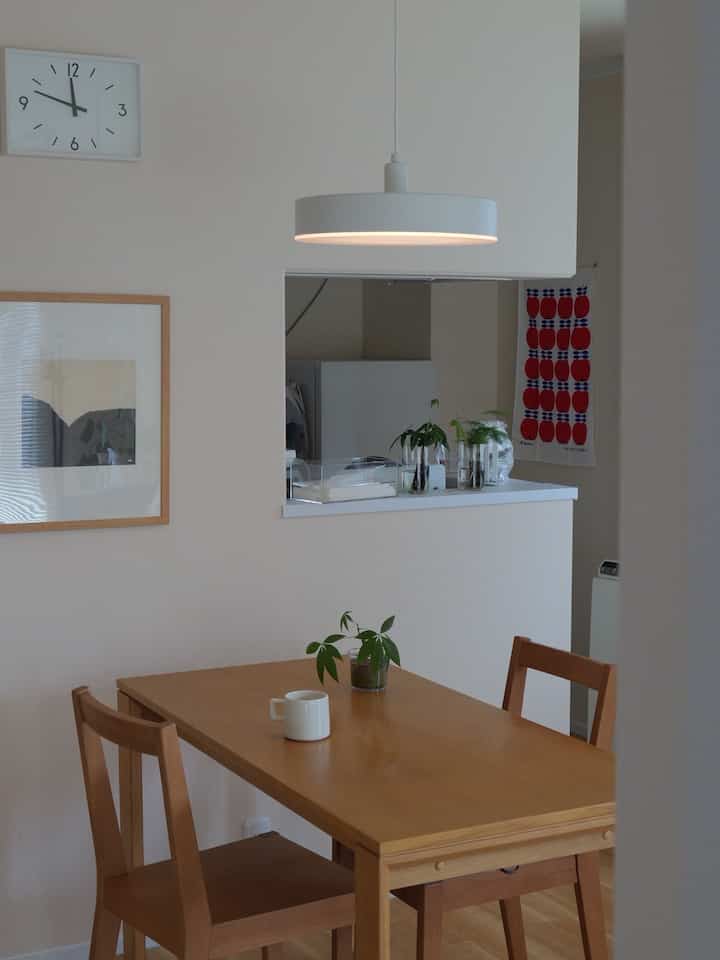 白い壁と木目調のダイニングテーブルと椅子が配置された北欧風の清潔感のあるダイニングスペース