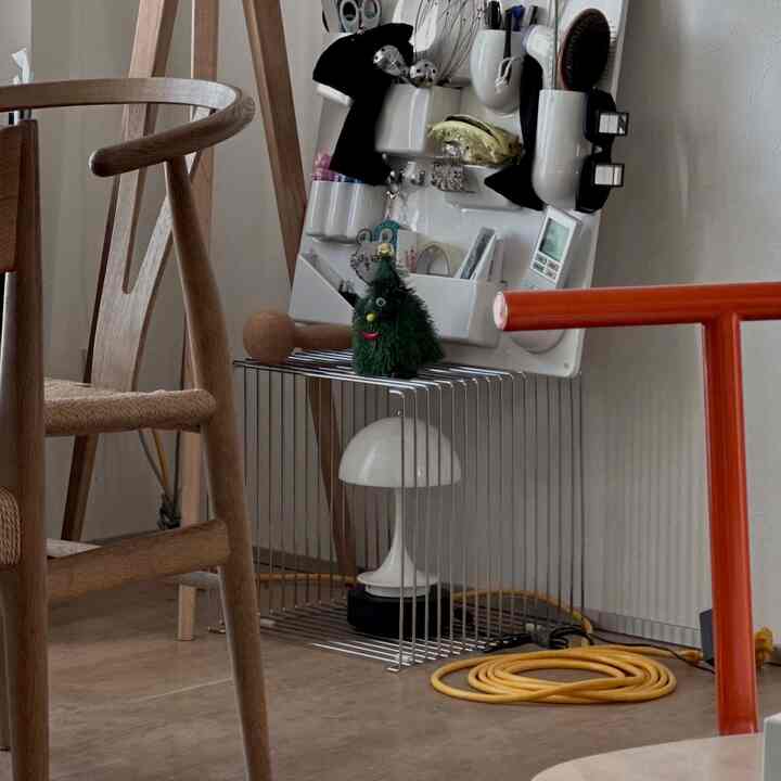 ナチュラルな色調のリビング、木製チェアと白い壁掛け収納が配置された清潔感のある空間