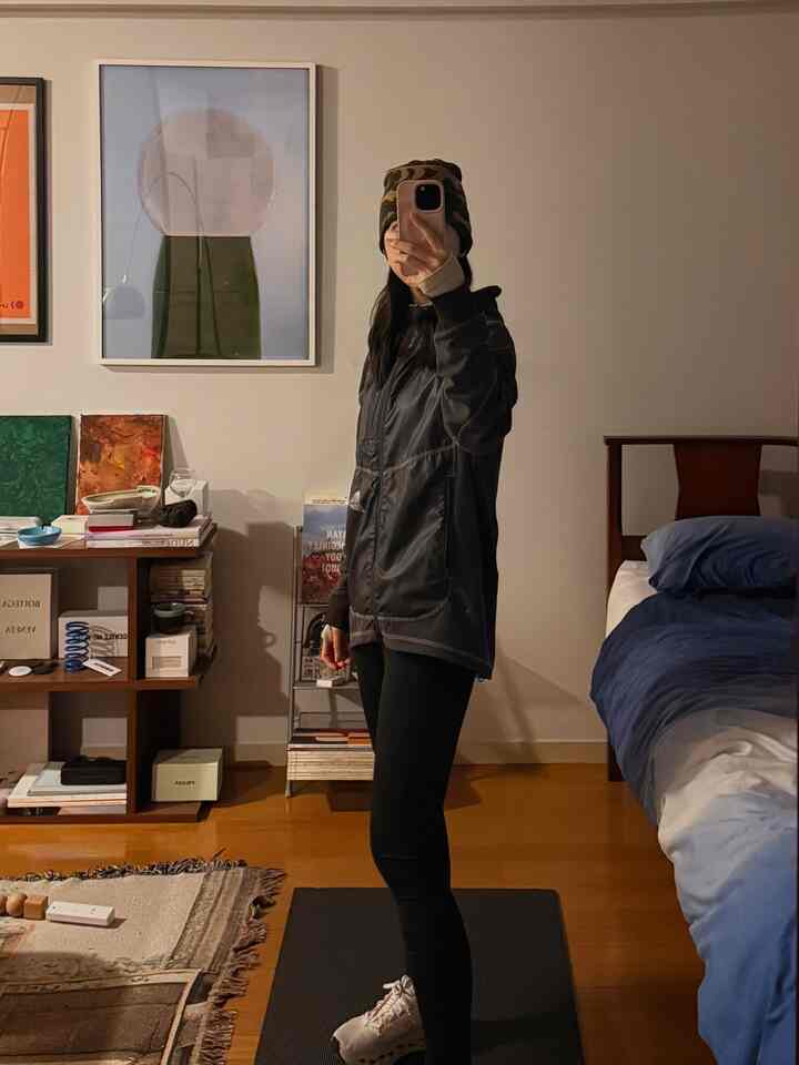 Mid-Century Modern studio bedroom with brown wood flooring and blue bedding, featuring a full-length mirror and bookshelf in a cozy setting