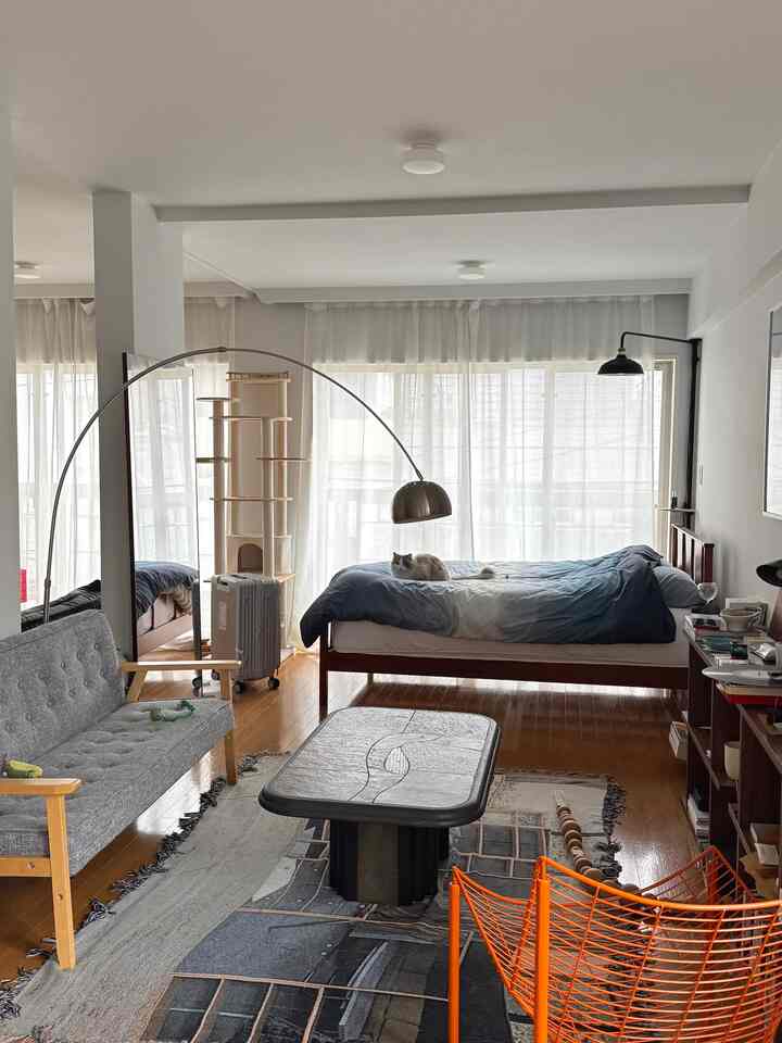 ブラウンの木目調フローリングと家具が映えるナチュラルモダンな寝室、猫とキャットタワーが配置された落ち着いた雰囲気の空間